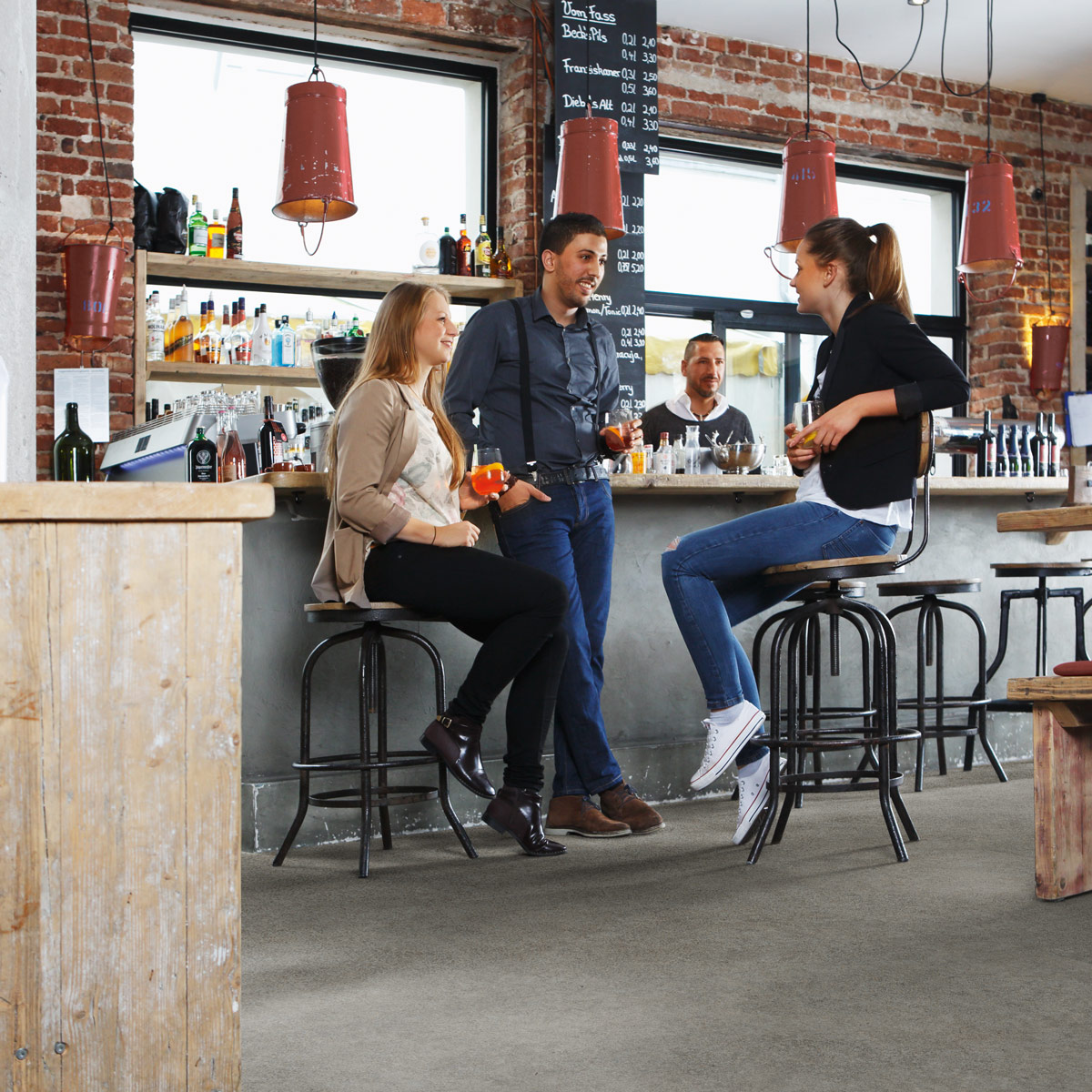 wineo Bodenbelag Designboden Grau Steinoptik Menschen in einem Café